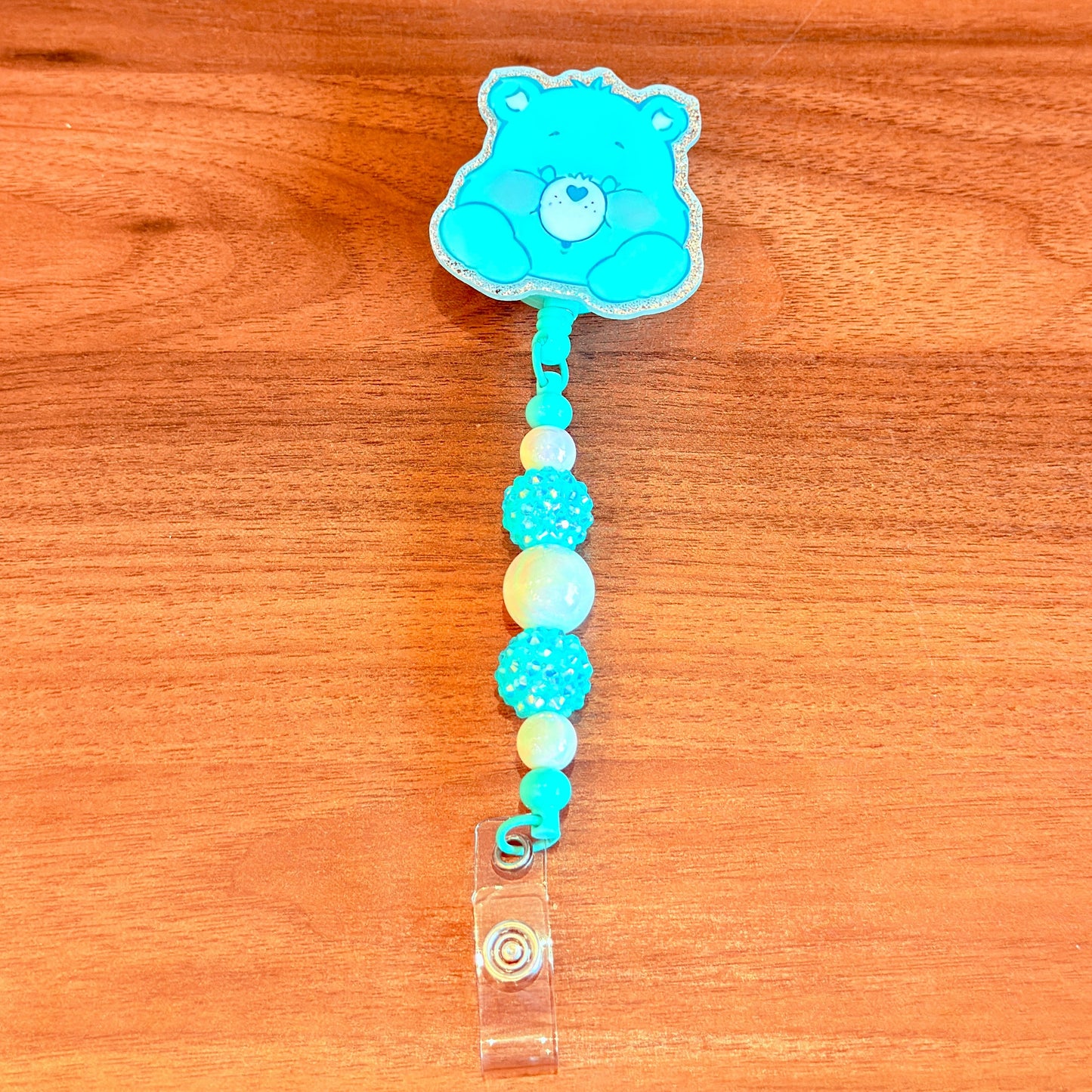 Blue bear-shaped badge holder with colorful beads on a wooden surface