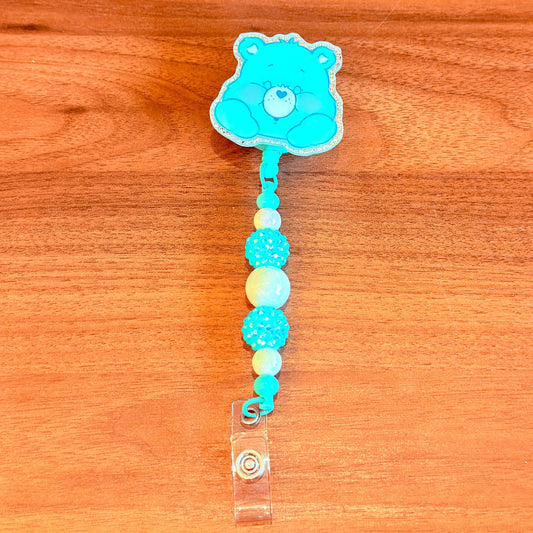 Blue bear-shaped badge holder with colorful beads on a wooden surface